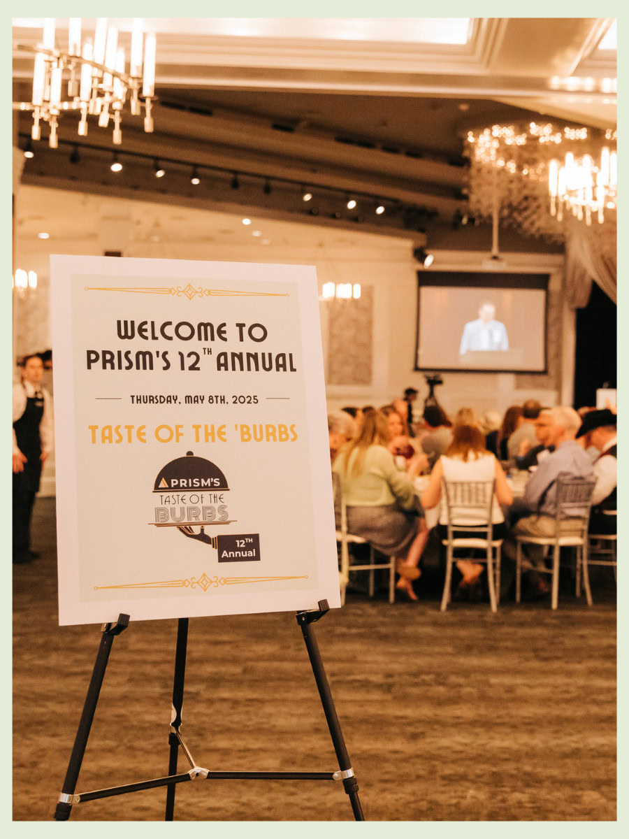 a picture of an open ballroom with guests seated at tables. On the left of the image is a welcome sign. 